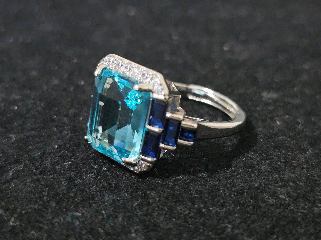 Essentials Blue Radiance ring with emerald-cut blue simulated topaz, white crystal accents, 18K white gold-plated, adjustable size L to R
