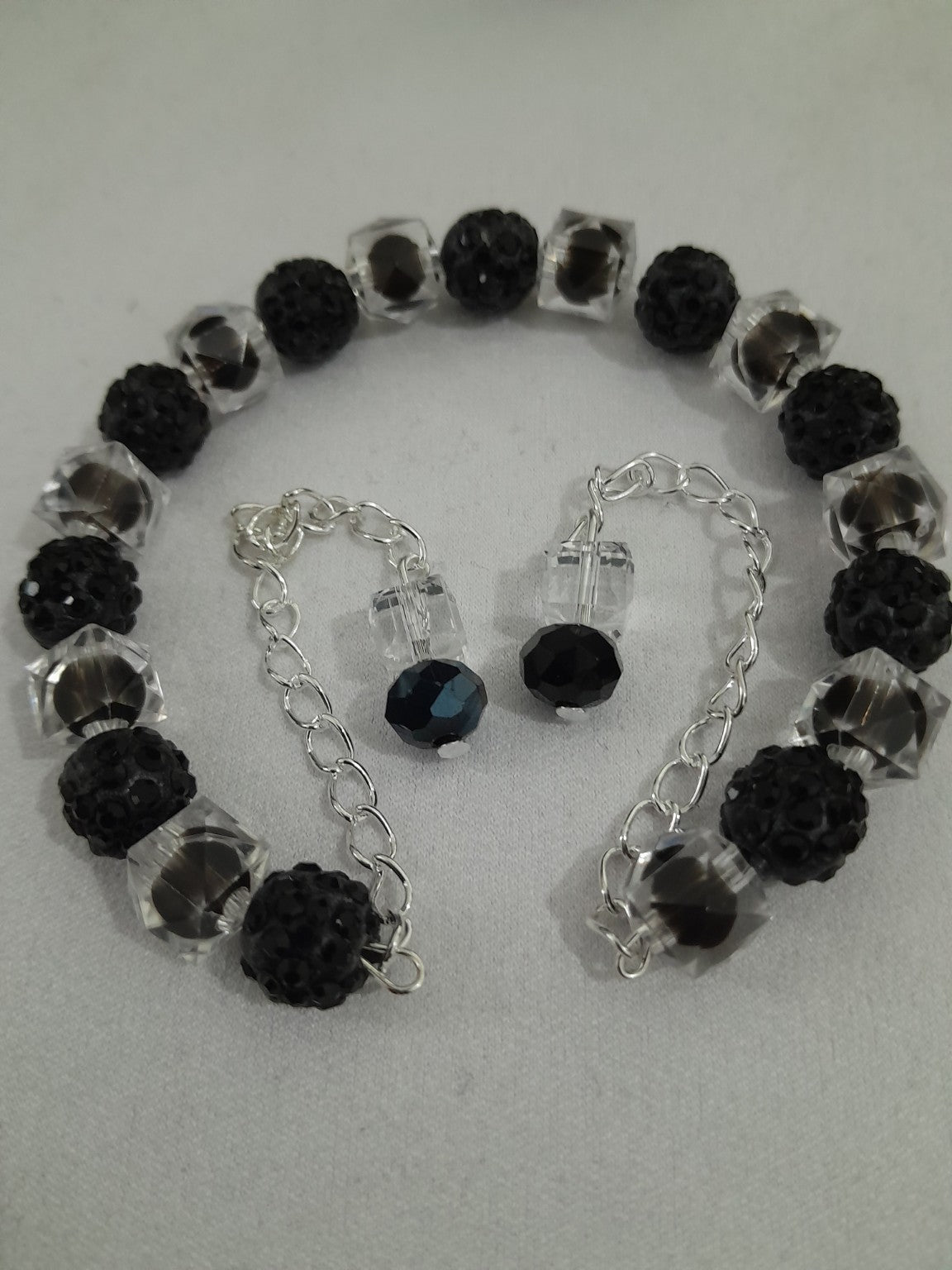 Black and clear beaded bracelet with faceted and textured beads, open-ended slip-on design with dangle chain accents for modern style
