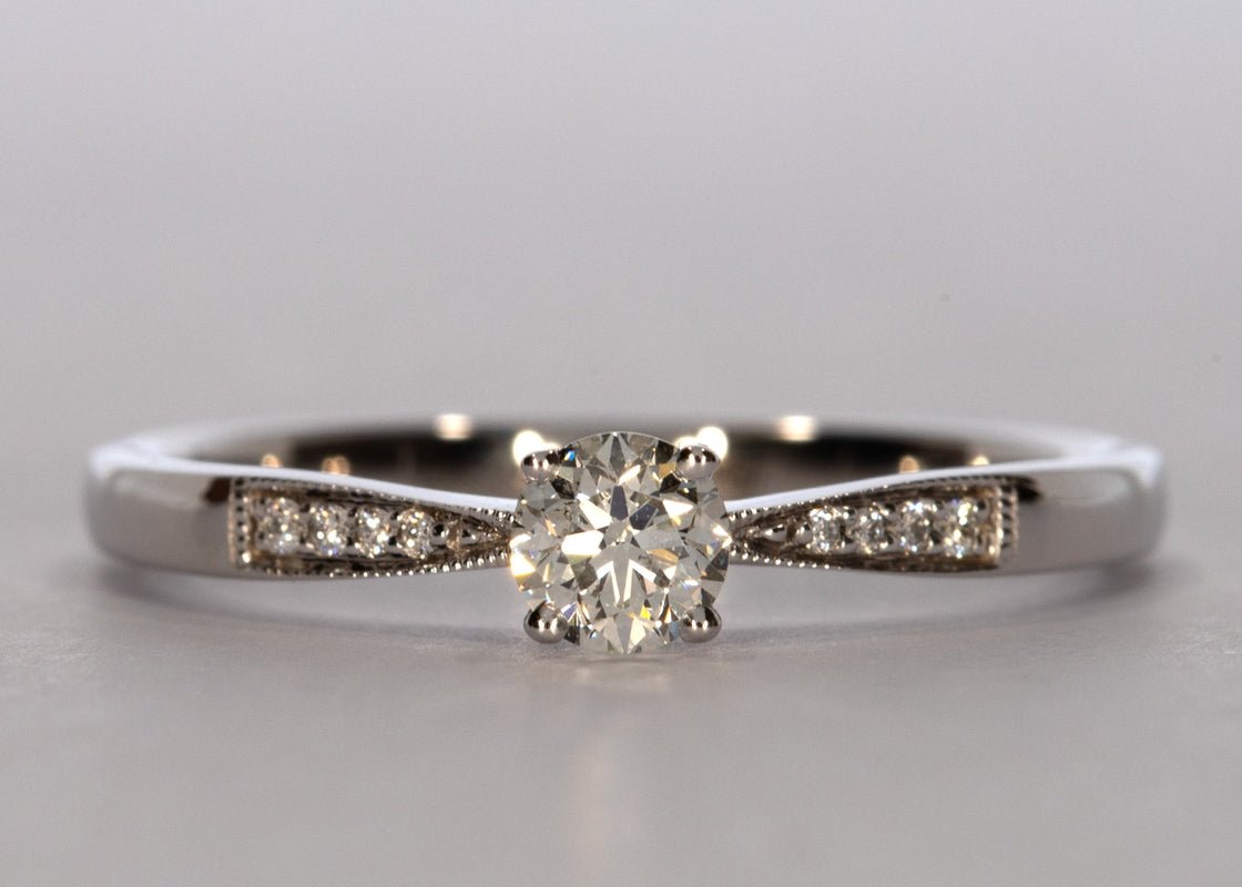 Delicacy Vintage ring in White Gold set with a Round 0.30ct. H - White SI1 - Slightly Included Natural Diamond. With 0.04ct of round brilliant diamonds set on a 2mm band, which tapers delicately toward the centre diamond. - Prestige Stones