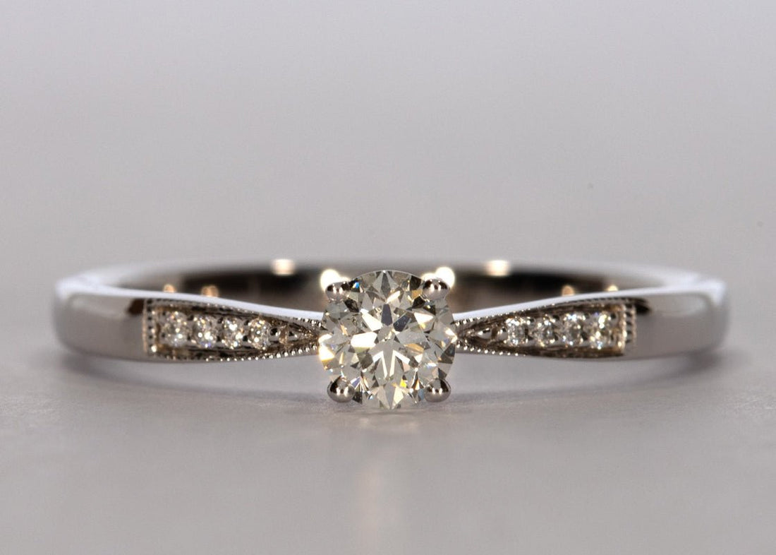 Delicacy Vintage ring in White Gold set with a Round 0.30ct. H - White SI1 - Slightly Included Natural Diamond. With 0.04ct of round brilliant diamonds set on a 2mm band, which tapers delicately toward the centre diamond. - Prestige Stones