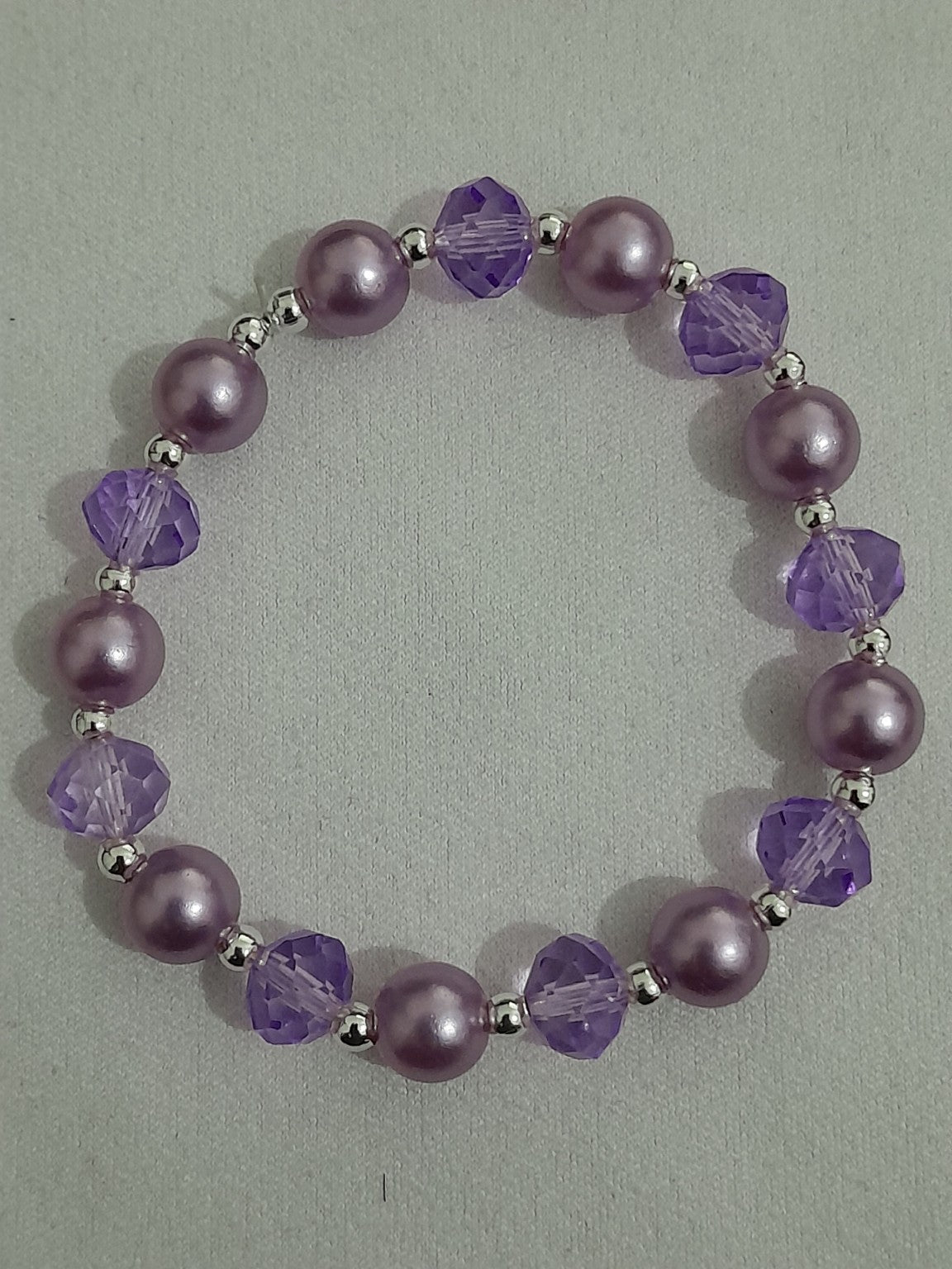 Purple stretch bracelet with pearl-style beads, faceted crystal-cut beads, and silver-tone spacers