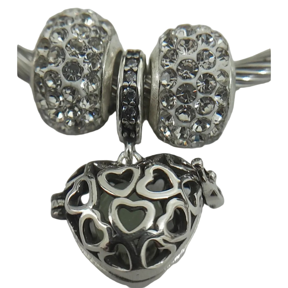 Silver-plated twisted-wire cable bangle with pavé crystal beads and filigree heart charm, flexible open-ended design for everyday wear