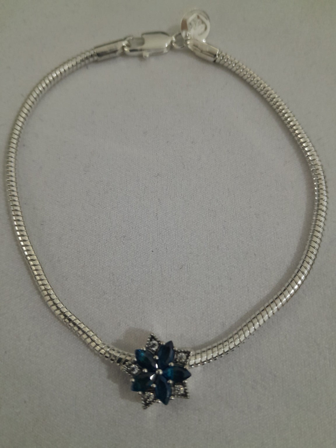 Silver-plated snake-chain bracelet with deep blue marquise crystals floral charm and clear pavé accents