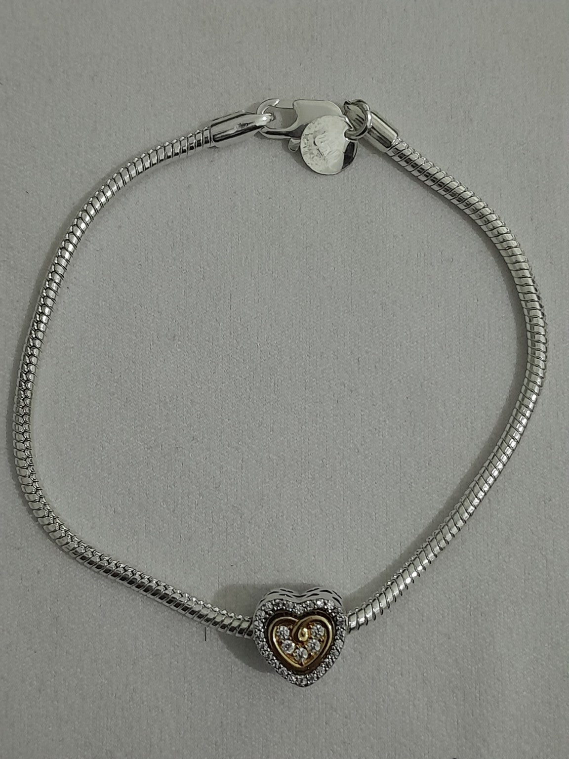 Two-tone heart charm bracelet with gold-tone inner heart, clear crystals, pavé accents, and polished snake chain